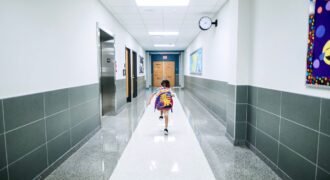 A child runs through a bright school hallway, emphasizing modern architecture and energy.